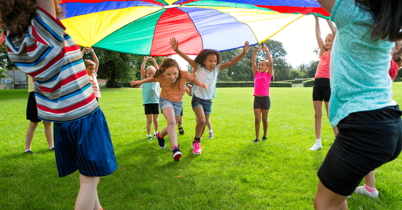 Kids playing outdoors with a play parachute