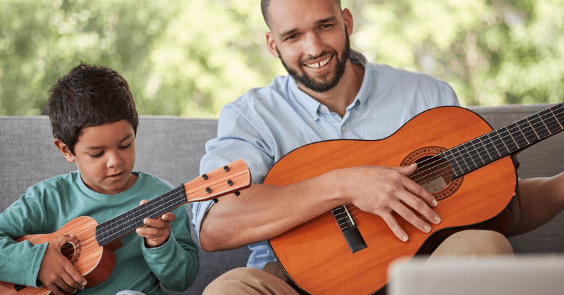 Dad and young boy playing their own guitars