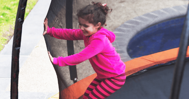 Young girl playing inside an enclosed trampoline