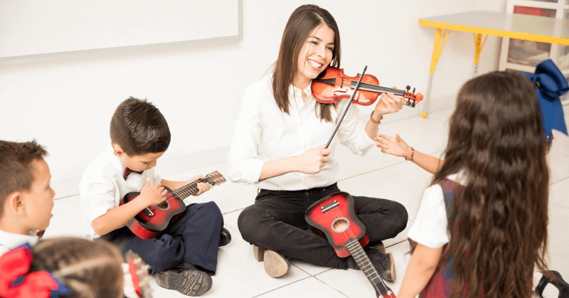 Music teacher showing kids how to play violin