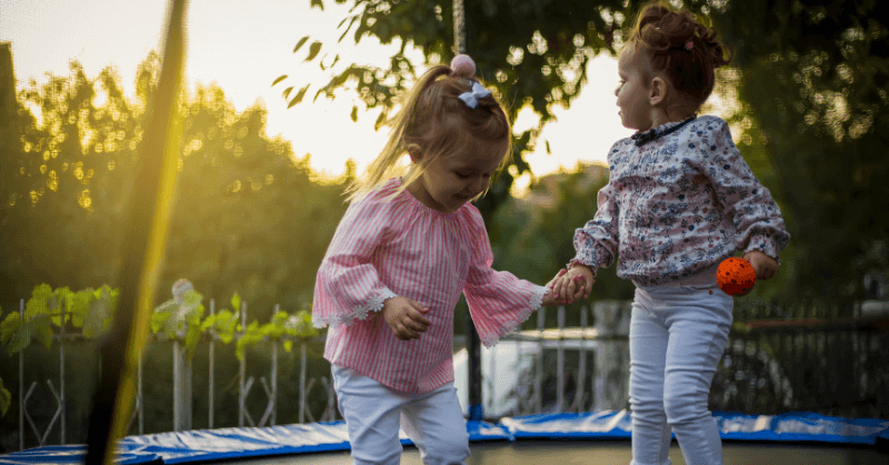 Two little girls standing on a trampoline