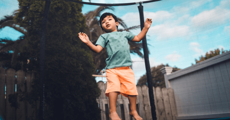 Little boy jumping inside a netted trampoline