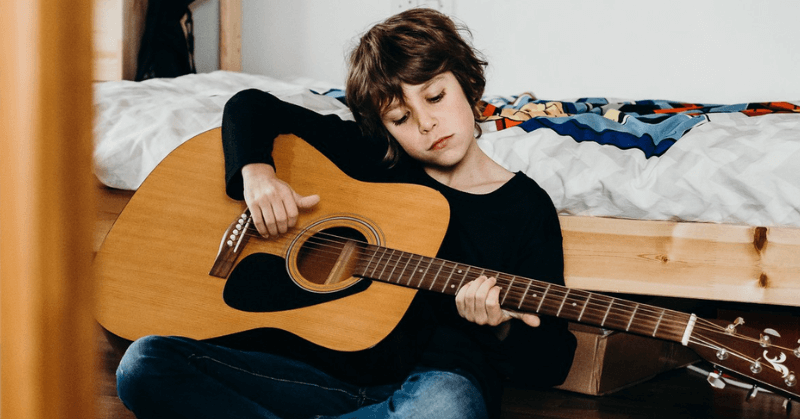 Young boy practising on a full-sized guitar